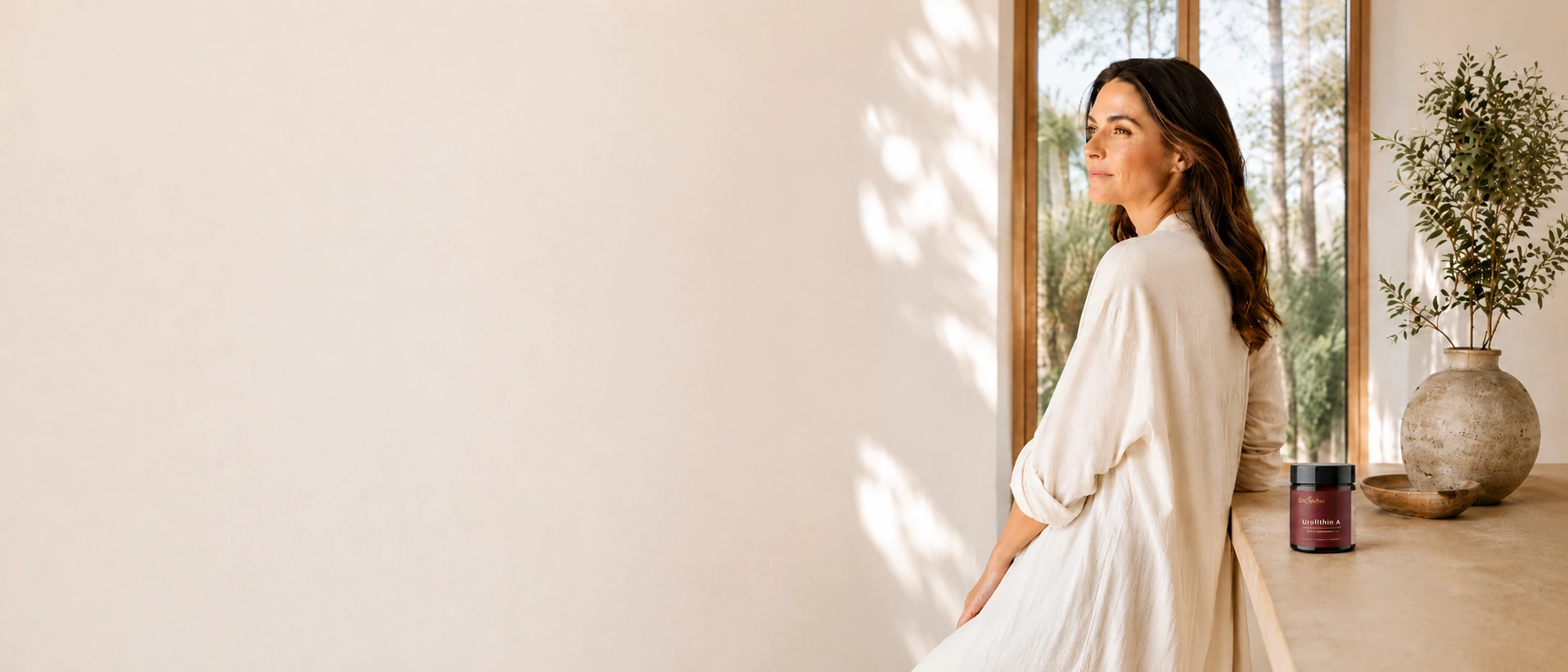 Woman standing beside BioFianne Urolithin A supplement in a bright wellness-inspired interior